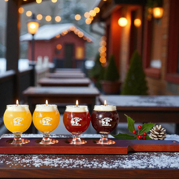  Four glasses of beer on a wooden tray with lit candles, set against a festive outdoor background holiday gifts by CW Candle Co. North Carolina 