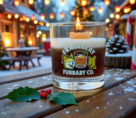Glass candle with 'FRAGEELAY FURBABY CO. CW Candle Co. branding on a wooden table outdoors during winter. Holiday Candle. 