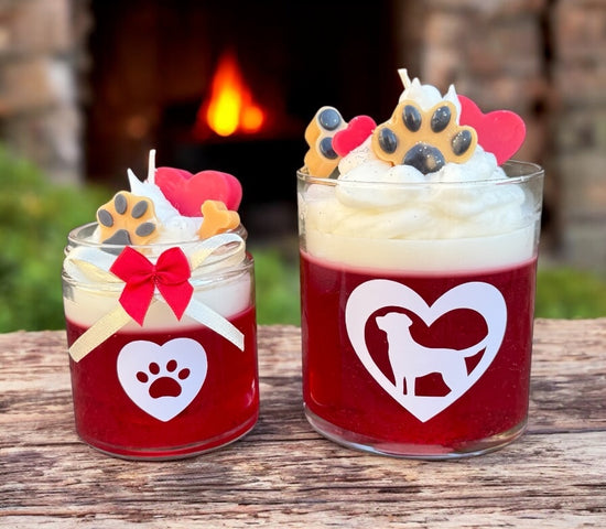 Two red coconut rose scent fur baby candles with whipped wax, dog-themed decorations, and a fireplace in the background.