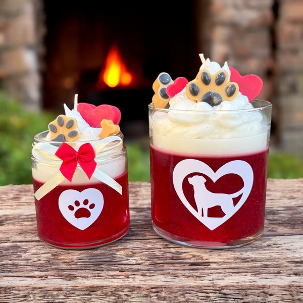  Two red coconut rose scent fur baby candles with whipped wax, dog-themed decorations, and a fireplace in the background.