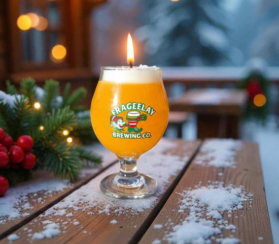 Candle in a glass with a Frageelay  logo on a wooden table outdoors during winter by CW Candle Co. North Carolina 