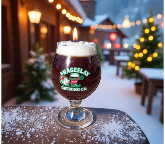 Glass of dark beer holiday candle with foam on a wooden table outdoors at night, featuring Frageelay Brewing Co. branding by CW Candle Co. North Carolina 