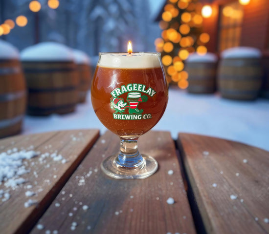Glass of Frageelay Brewing Co. holiday beer  candle on a wooden table with a snowy background by CW Candle Co. North Carolina 